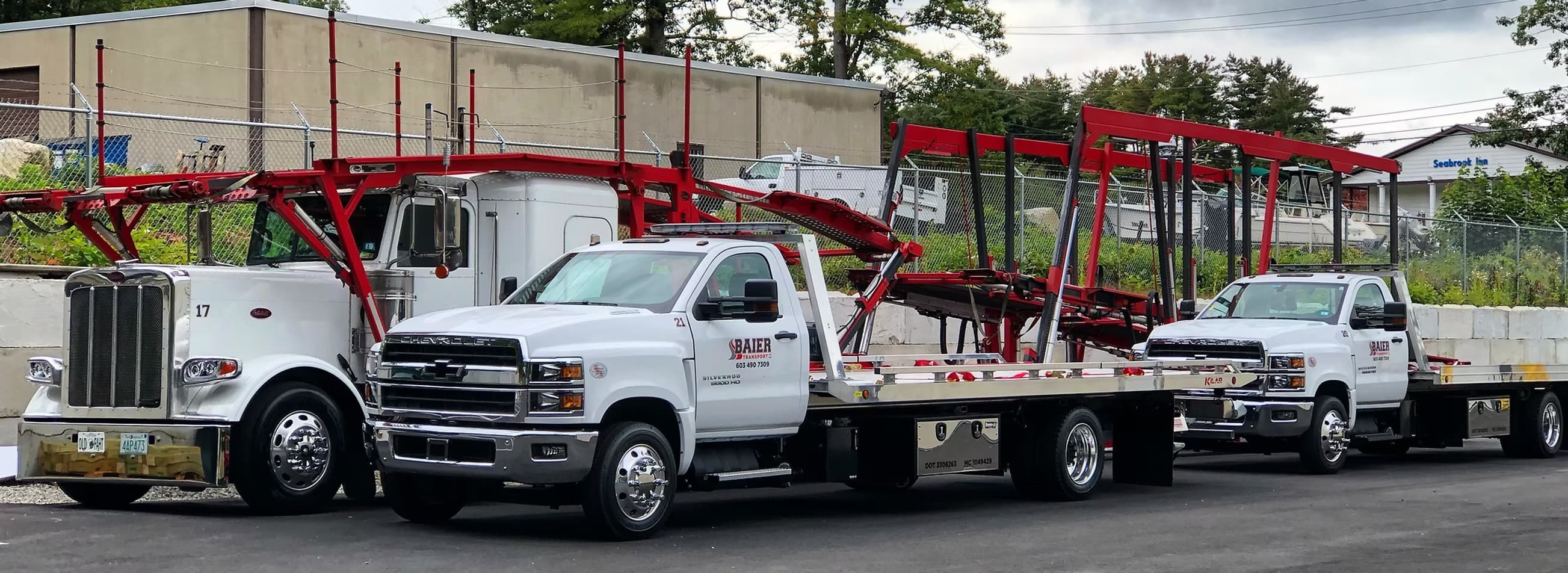 Baier Transport full fleet lineup showing Peterbilt car carrier, Chevy Silverado 5500 flatbed, and tow truck at Seabrook NH