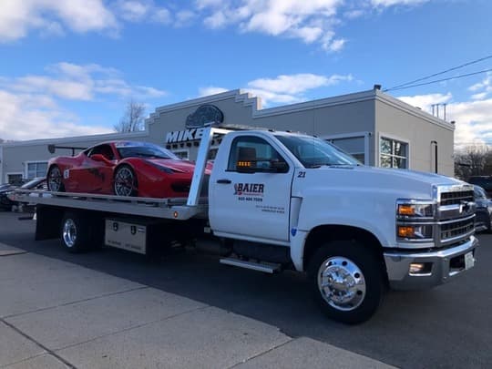 Red Ferrari 488 secured on Baier Transport branded Chevy Silverado 5500 flatbed truck for exotic and luxury car shipping