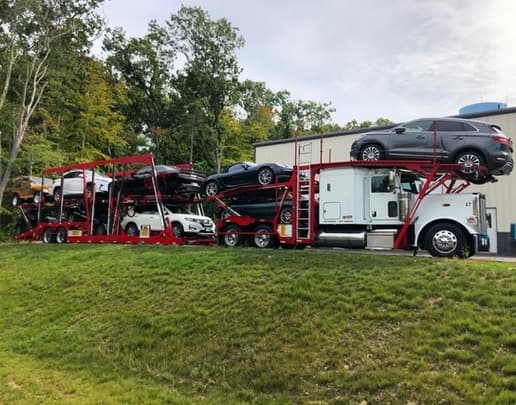 Fully loaded Baier Transport car carrier departing in autumn — fleet management and multi-vehicle logistics