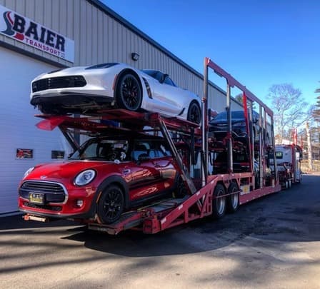 Red Mini Cooper and white Chevrolet Corvette loaded on car carrier at Baier Transport facility