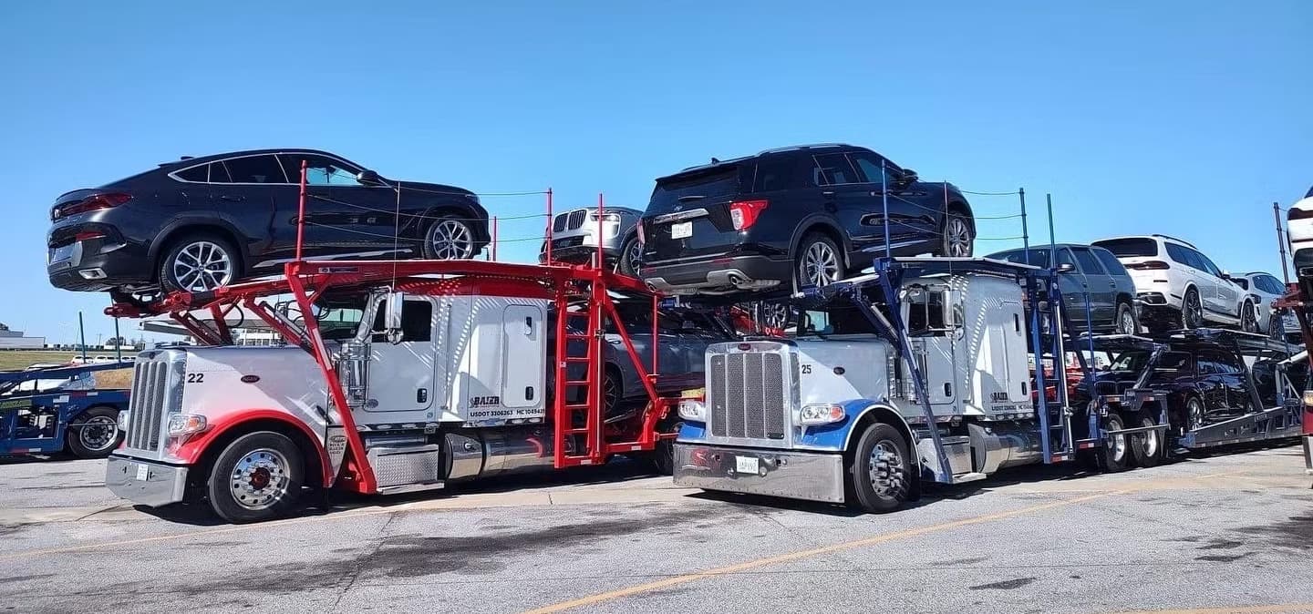 Two Peterbilt open car carriers fully loaded with Ford F-150 trucks and SUVs ready for nationwide auto transport shipping